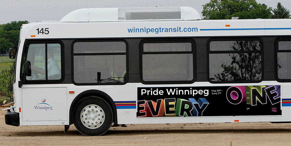 This image shows a Winnipeg Transit bus with an advertisement for Pride Winnipeg 2025. The advertisement on the side of the bus features the words EVERY ONE stacked vertically in large colorful three-dimensional lettering, along with the Pride Winnipeg logo and the dates May 30th to June 2nd. The bus is white with blue and red stripes along the side. The number 145 is visible above the front window. The website winnipegtransit.com is printed along the top of the bus. The bus is outdoors on a gravel surface with trees in the background.